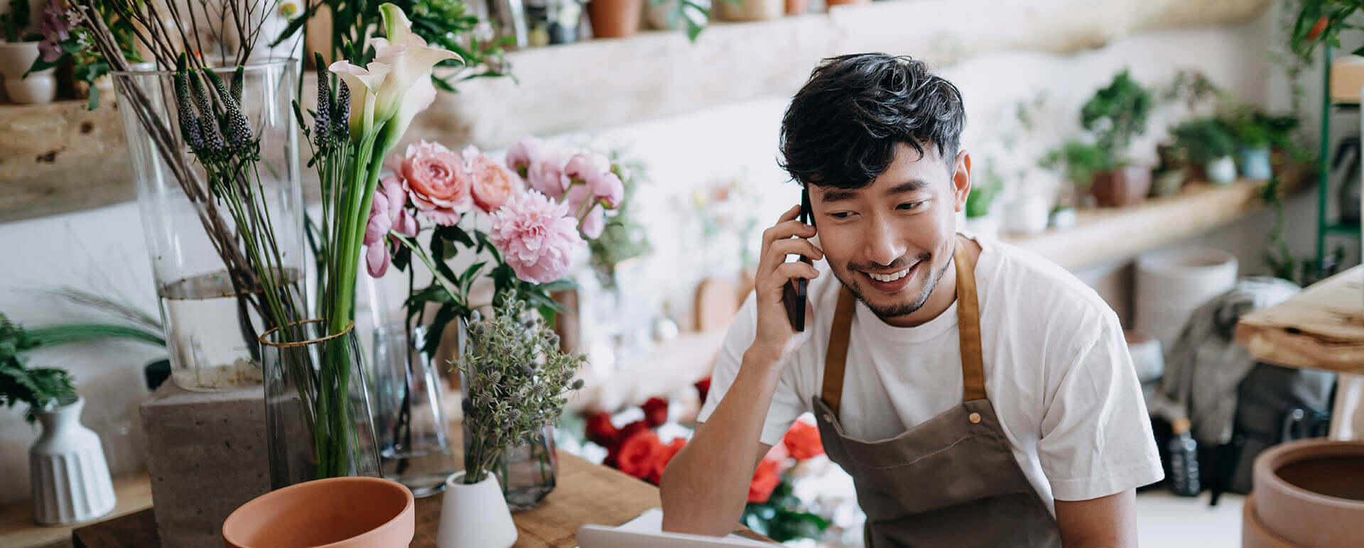 Business owner talking on the phone while working on a laptop.