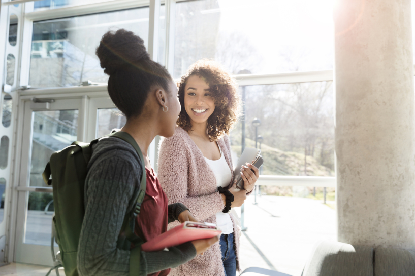 Two students walk through a building while talking.