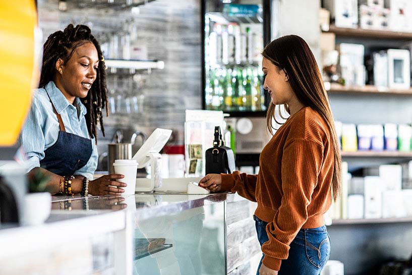 A woman buys a cup of coffee with a debit card.