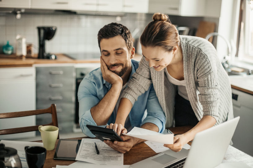 Two people work with a laptop, printouts, and mobile device.